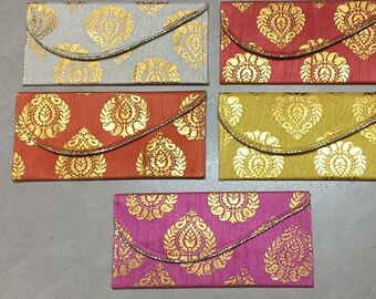 May include: Five colorful clutch purses with gold floral patterns. The purses are in shades of gray, red, orange, green, and pink. Each purse has a curved flap and a silver trim. The purses are rectangular and appear to be made of fabric.