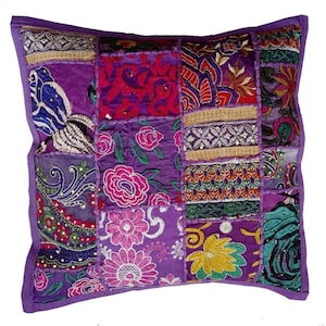 Puede incluir: Almohada de patchwork morado con bordado floral y lentejuelas. La almohada está hecha de diferentes telas y tiene una variedad de colores y patrones.