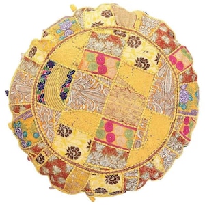Peut inclure: Un coussin de sol rond jaune en patchwork avec une variété de motifs brodés colorés. Le coussin est fait de chutes de tissu cousues ensemble en forme circulaire.
