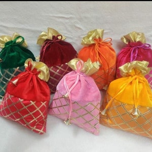 Könnte beinhalten: Sortiment aus bunten Samt-Kordelbeuteln mit goldenen Verzierungen. Die Beutel sind in den Farben Grün, Rot, Orange, Rosa und Gelb.