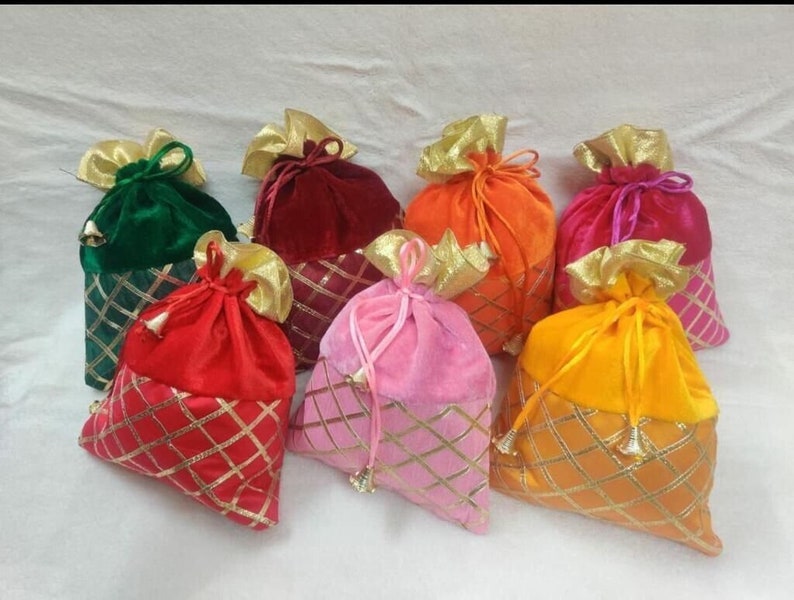 May include: Assortment of colorful velvet drawstring bags with gold trim. The bags are in shades of green, red, orange, pink, and yellow.