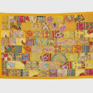 May include: A rectangular patchwork textile with a yellow border. The patchwork is composed of numerous small, rectangular fabric pieces in shades of yellow, pink, red, blue, and green. Each piece features a unique floral or paisley pattern.