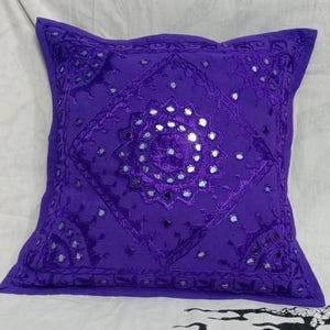 May include: Purple velvet pillow with embroidered floral design and mirrored accents.
