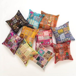 Könnte beinhalten: Sortiment bunter Patchwork-Wurfkissen mit verschiedenen Stickereien. Die Kissen sind aus verschiedenen Stoffen gefertigt und haben unterschiedliche Muster und Farben.