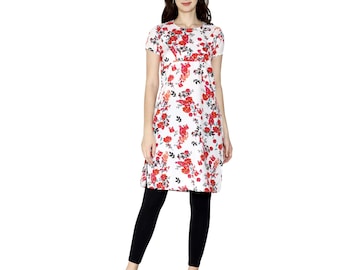 Puede incluir: Una mujer con un vestido túnica blanco con estampado floral rojo y leggings negros. El vestido tiene mangas cortas y cuello redondo. La mujer lleva sandalias doradas.