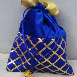 May include: A blue velvet drawstring bag with gold accents. The bag has a gold and blue geometric pattern and gold tassels.