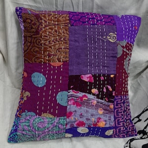 May include: Purple and brown patchwork cushion cover with a kantha stitch design. The cushion cover is made from recycled saris and is a unique and handmade item.