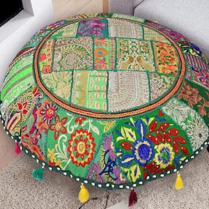 May include: A round green floor cushion with a patchwork design of colorful fabric squares and embroidered flowers. The cushion has a white border and white tassels.