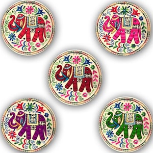 Könnte beinhalten: Set aus vier runden Untersetzern mit bunten gestickten Elefanten mit Blumendesigns. Die Elefanten sind rot, rosa, lila und grün.