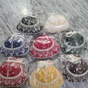 May include: A collection of beaded drawstring bags in various colors, including black, white, blue, red, green, yellow, and brown. Each bag is packaged in clear plastic and features intricate beadwork around the base and top.