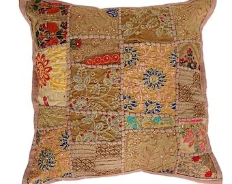 May include: A square throw pillow with a patchwork design. The pillow is made of various fabrics in shades of brown, beige, and gold. The fabric is decorated with colorful embroidery and sequins.