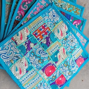 Puede incluir: Conjunto de cuatro manteles individuales cuadrados de tela azul turquesa con diseños de patchwork bordados de colores. Los manteles individuales están hechos de una variedad de telas y presentan bordados intrincados.