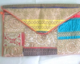 Pode incluir: Uma bolsa de mão de patchwork colorida com um design bordado em ouro e prata. A bolsa tem um fecho de aba e uma alça de corrente.