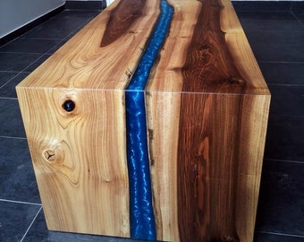 May include: A wooden coffee table with a blue resin river running through the center. The table is made of light and dark wood.