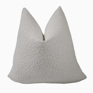 May include: White throw pillow with a textured fabric. The pillow is square shaped and has a simple design.