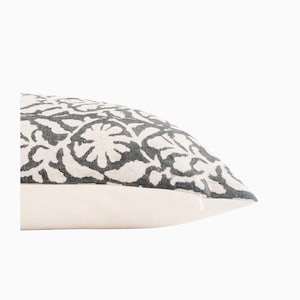 May include: A white pillow with a gray floral pattern. The pillow has a zipper closure.