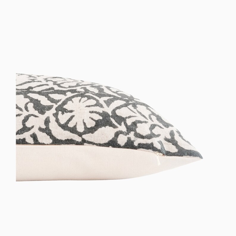 May include: A white pillow with a gray floral pattern. The pillow has a zipper closure.