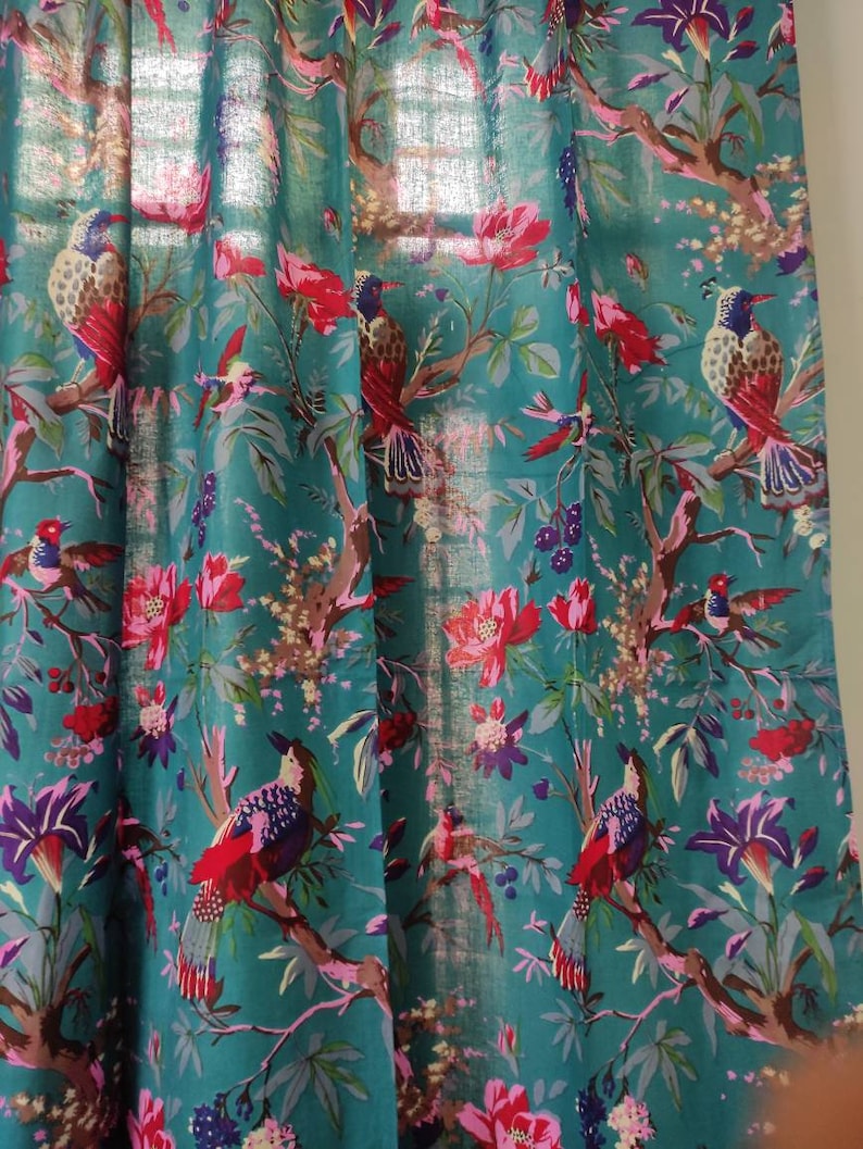 Puede incluir: Panel de cortina de color turquesa con un estampado floral y de aves vibrante. El dise&ntilde;o presenta flores rojas, rosas y moradas, junto con p&aacute;jaros coloridos posados en ramas. La tela es ligeramente transparente.