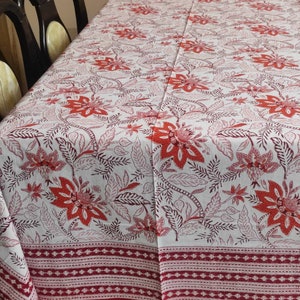 May include: White tablecloth with a red floral pattern. The tablecloth has a red border with a white and red patterned trim.