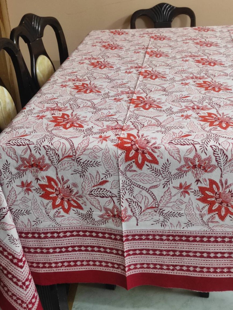 May include: White tablecloth with a red floral pattern. The tablecloth has a red border with a white and red patterned trim.