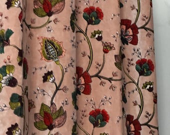 May include: A close-up of a pink curtain with a floral pattern. The design features red, green, and white flowers with dark green stems and leaves. The curtain is made of a soft, velvety material.