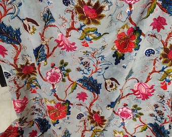 Könnte beinhalten: Ein hellblauer Stoff mit einem Blumendruck. Die Blumen sind in den Farben Rosa, Rot und Weiß gehalten. Der Stoff hat einen Vintage-Look.