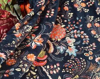 May include: A dark blue fabric with a floral pattern in shades of orange, pink, yellow, and green. The fabric has a velvety texture.