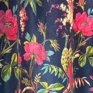 Könnte beinhalten: Ein dunkelblauer Stoff mit einem floralen Muster mit rosa Rosen, grünen Blättern und einem gelben und braunen Pfauenmuster.