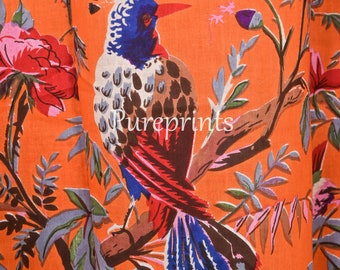 May include: Orange fabric with a colorful bird and floral print. The bird is blue, red, and brown with a long tail. The flowers are pink, red, and purple.