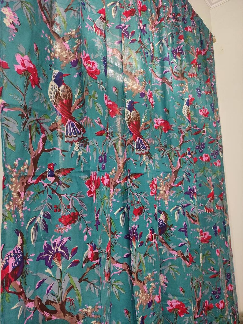 Puede incluir: Panel de cortina de color turquesa con un estampado floral y de aves vibrante. El dise&ntilde;o presenta flores rojas, rosas y moradas, junto con ilustraciones detalladas de aves posadas en ramas. La cortina es de tela ligera.