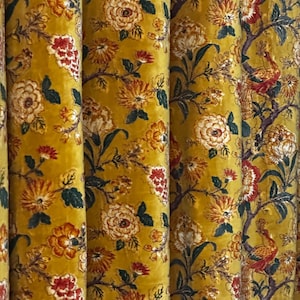 May include: Close-up of a mustard-yellow floral fabric with a velvet texture. The design features large, stylized flowers in shades of cream, orange, and red, along with green leaves. The fabric is likely used for curtains or upholstery.