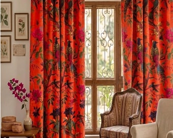 May include: A pair of floor-length curtains in a vibrant orange fabric featuring a repeating pattern of dark birds, green foliage, and pink flowers. The curtains hang from a metal rod and display a rich, saturated color palette throughout the design.