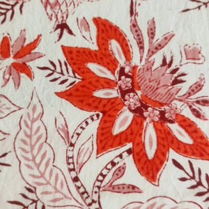 May include: A white fabric with a red and pink floral pattern. The flowers are intricate and detailed, with a variety of shapes and sizes. The fabric is soft and smooth, and would be perfect for a variety of projects.