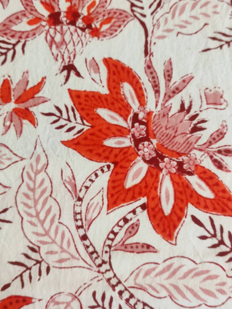 May include: A white fabric with a red and pink floral pattern. The flowers are intricate and detailed, with a variety of shapes and sizes. The fabric is soft and smooth, and would be perfect for a variety of projects.