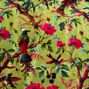 以下が含まれることがあります： 緑色のベルベット生地に、花と鳥の模様が描かれています。花はピンクで、鳥はカラフルです。