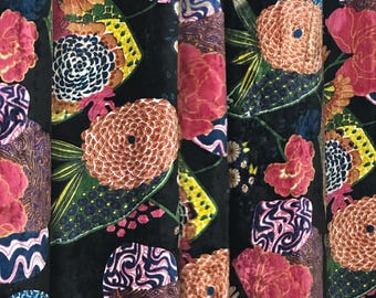 Könnte beinhalten: Schwarzer Samtstoff mit einem bunten Blumenmuster. Die Blumen sind rosa, rot, gelb und blau. Der Stoff hat eine strukturierte, fast 3D-Optik.