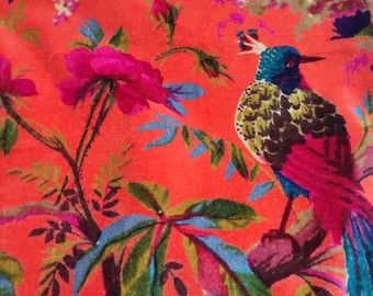 May include: A vibrant orange fabric with a floral and bird pattern. The fabric features a large, colorful bird perched on a branch with green leaves. The background is a bright orange with pink, purple, and green floral accents.