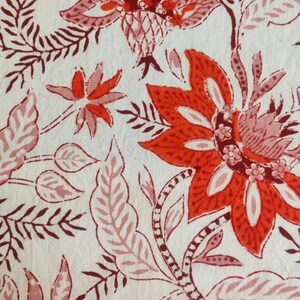 May include: A white fabric with a red and pink floral pattern. The flowers are stylized and have a traditional Indian design.