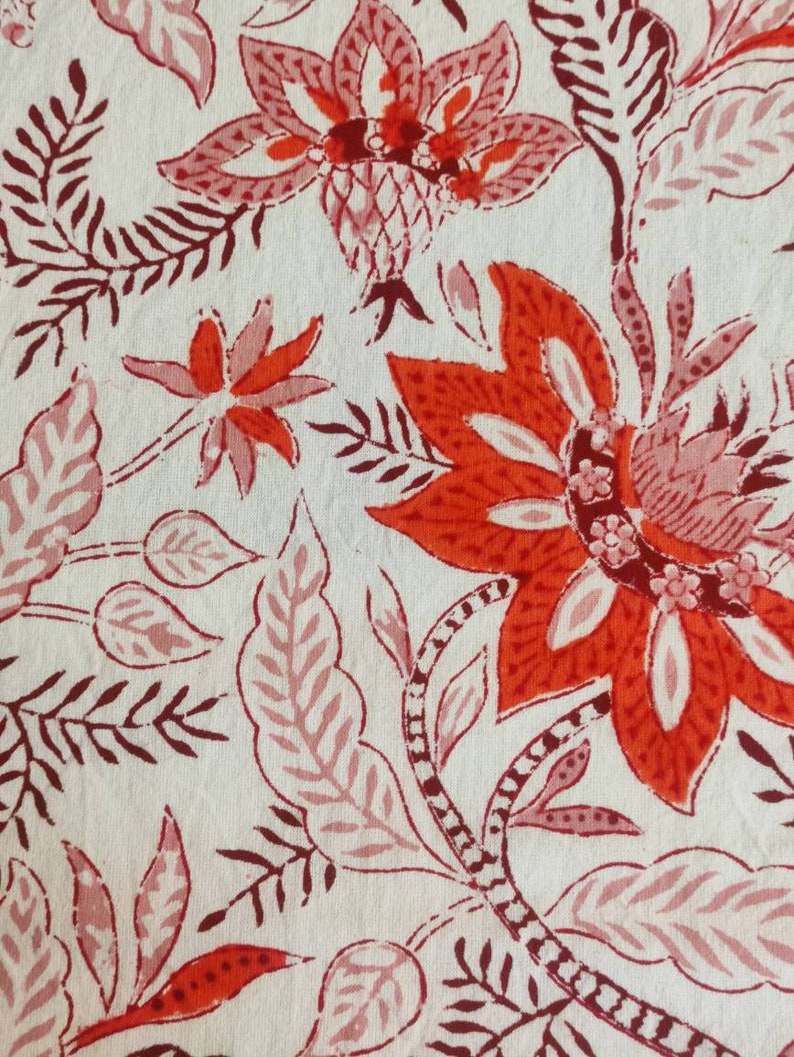 May include: A white fabric with a red and pink floral pattern. The flowers are stylized and have a traditional Indian design.