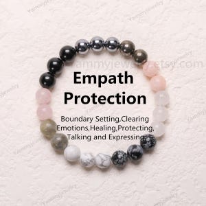 Könnte beinhalten: Ein Armband aus verschiedenen Steinen, darunter schwarze, weiße, graue und rosa Steine. Das Armband ist mit "Empath Protection" beschriftet und enthält den Text "Grenzen setzen, Emotionen klären, heilen, schützen, sprechen und ausdrücken".