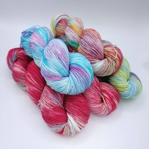 Image of 5 large twisted skeins of yarn stacked upon each other. Skeins are in shades of blue, red, purple and green.