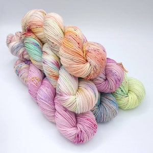 Image of 5 large twisted skeins of yarn stacked upon each other. Skeins are in shades of orange, pink, purple and green.