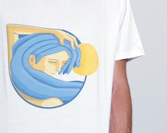 Puede incluir: Camiseta blanca con una ilustración azul y amarilla de una mujer con el pelo largo azul. La mujer mira hacia abajo y su pelo le cubre la cara.