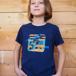 Puede incluir: Una camiseta azul marino con un gr&aacute;fico colorido de peces nadando en una escena submarina. El dise&ntilde;o incluye peces naranjas y azules, algas verdes y un fondo marino arenoso. La camiseta est&aacute; hecha de material suave.
