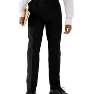 May include: Black dress pants with a straight leg, paired with black dress shoes. The pants are worn with a white button-down shirt. A book is held in one hand.