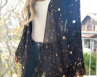 May include: A black sheer kimono with a gold moon and star pattern. The kimono has long sleeves and a relaxed fit.