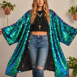 May include: A long, open-front sequin jacket in shades of teal and blue. The jacket is worn over a black crop top and blue jeans. The sequins create a shimmering effect, and the jacket has wide sleeves.