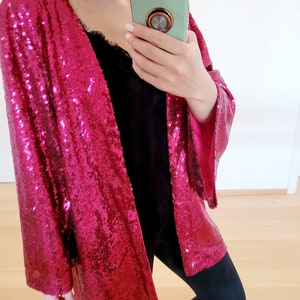 May include: A pink sequined cardigan with long sleeves and a loose fit.