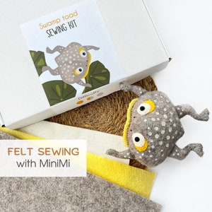 May include: A Swamp Toad sewing kit in a white box with a graphic of a toad on lily pads. The kit includes sheets of grey and yellow felt and a finished grey felt toad plush with white spots, yellow eye accents, and black pupils.