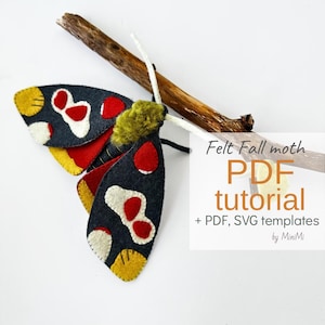 Può includere: Una falena di feltro con ali grigio scuro, macchie rosse e bianche e bordi gialli, posata su un rametto marrone. La falena ha un corpo verde e giallo e antenne bianche. Il testo sull'immagine recita "Felt Fall moth PDF tutorial".
